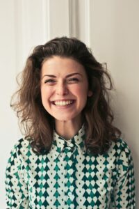 a woman with brown hair smiles as she wonders why do we call it a period