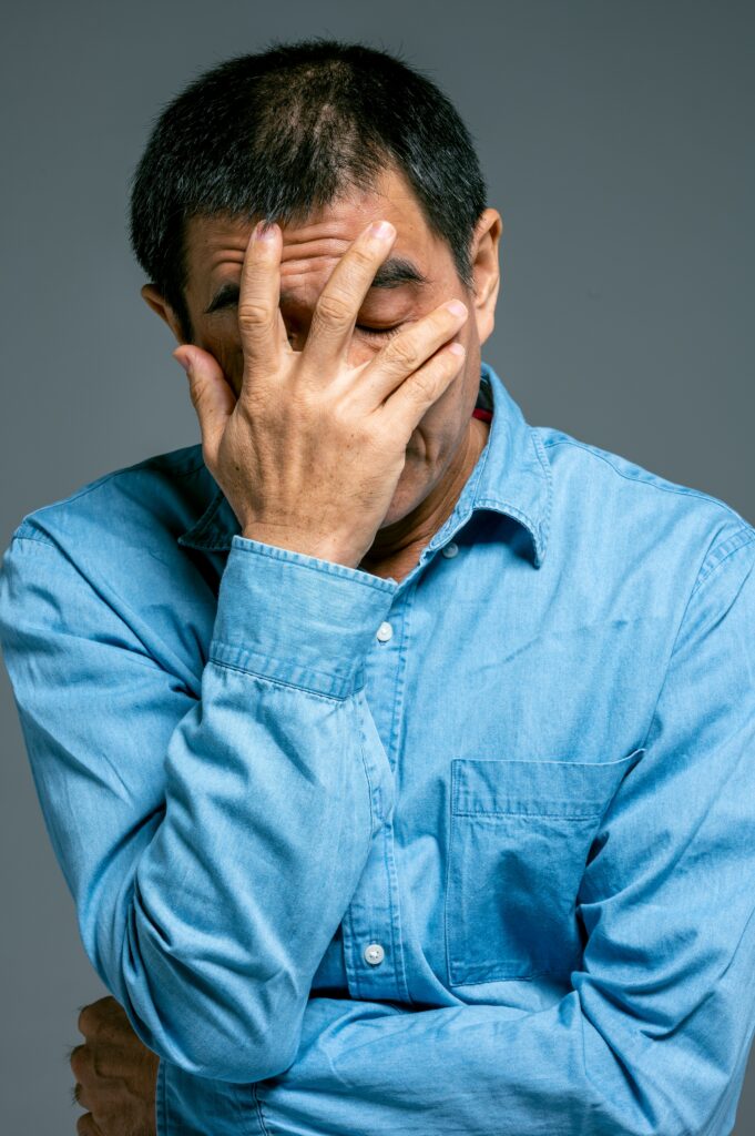 a man in a button up shirt has his hand over his face and his eyes closed