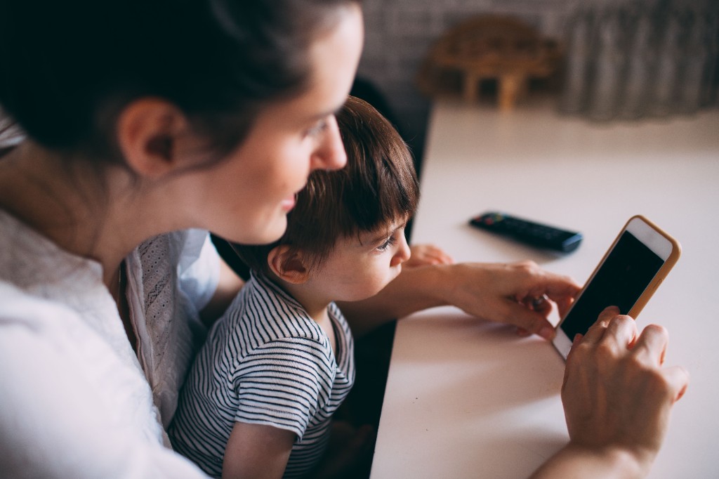 Caregiver and young child sharing attention on a phone