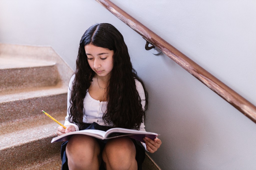 Child sitting alone on stairs reading a book