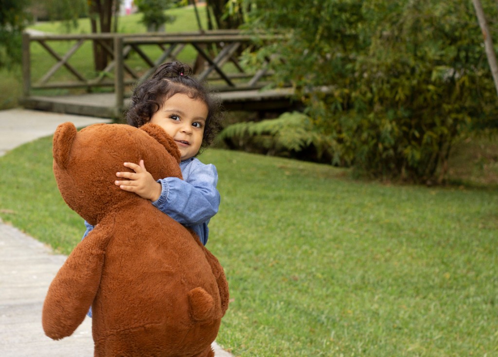 Young child hugging a large teddy bear outdoors