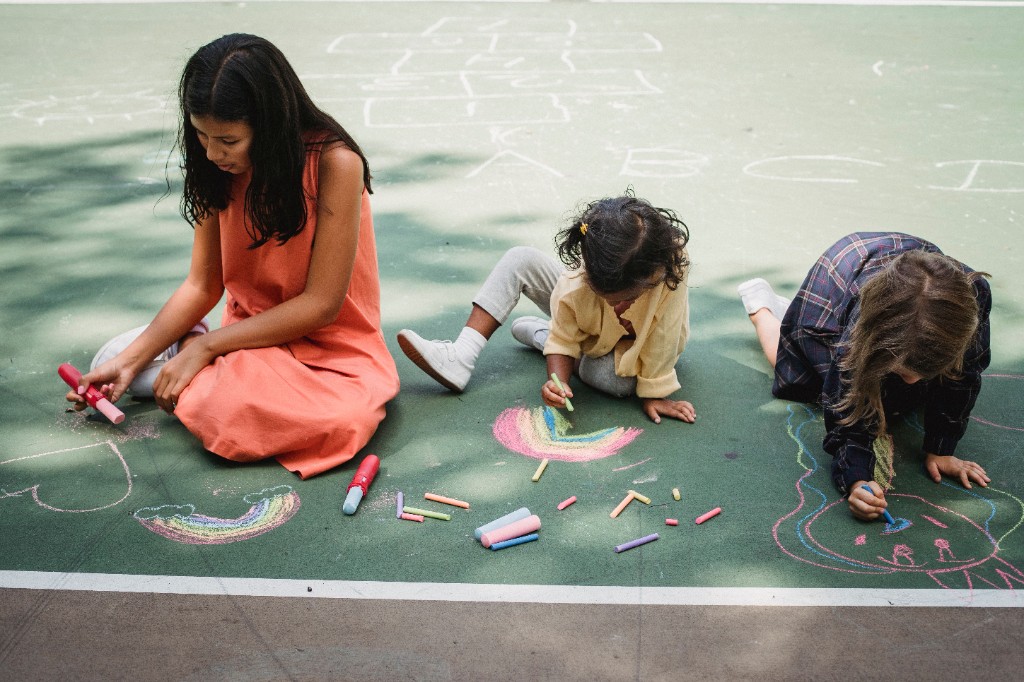 Adult and children drawing with chalk on a playground