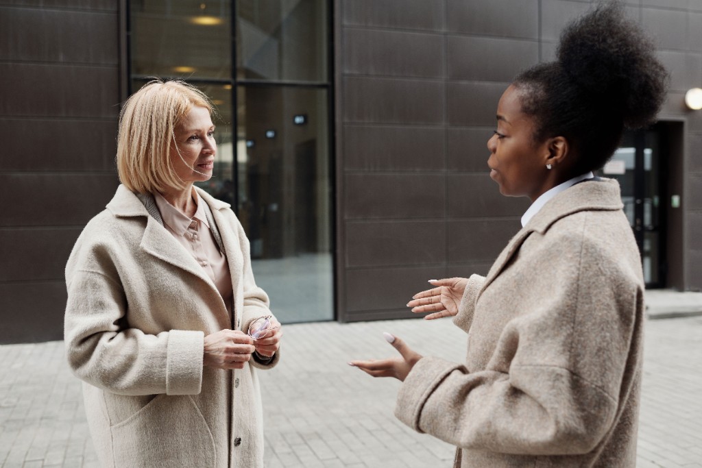 Two women in conversation outdoors, listening and speaking
